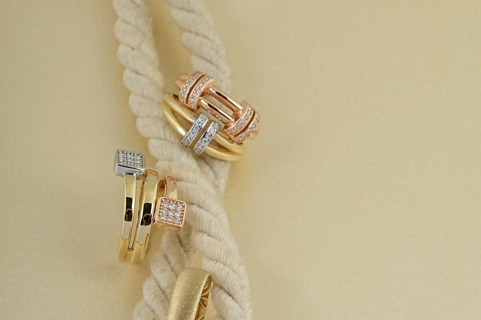 Luxurious gold and diamond rings displayed elegantly on a cream braided rope, creating a sophisticated look.
