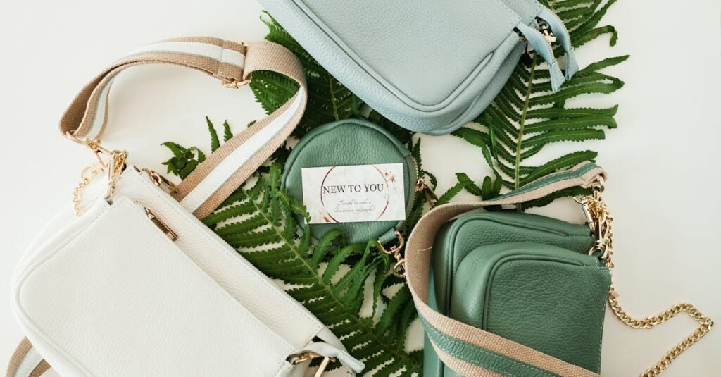 Flatlay of stylish leather handbags on a backdrop of green fern leaves. Perfect for fashion lovers.